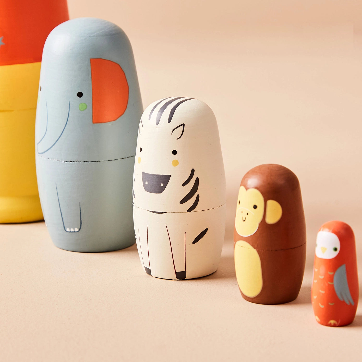 Set of colourful animal-shaped wooden dolls on a beige background