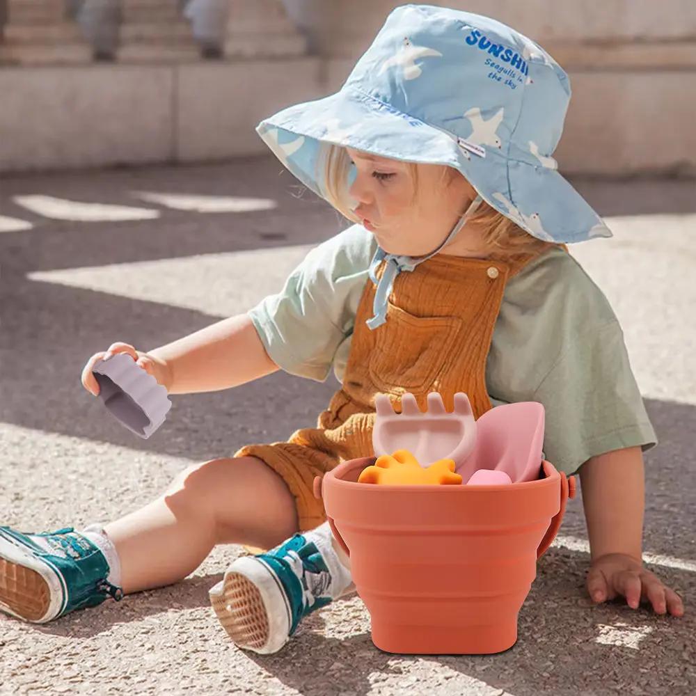 Child playing with silicone beach bucket and ocean-themed sand moulds in the sand