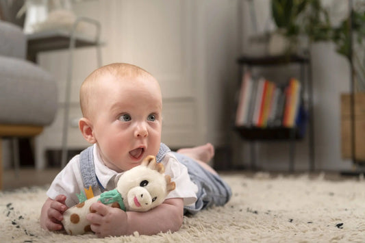 Baby holding and playing with Sophie la Girafe plush rattle