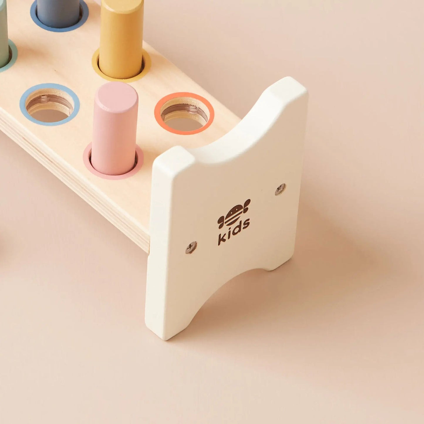 Children's wooden shape sorter with colourful cylindrical shapes on a beige background