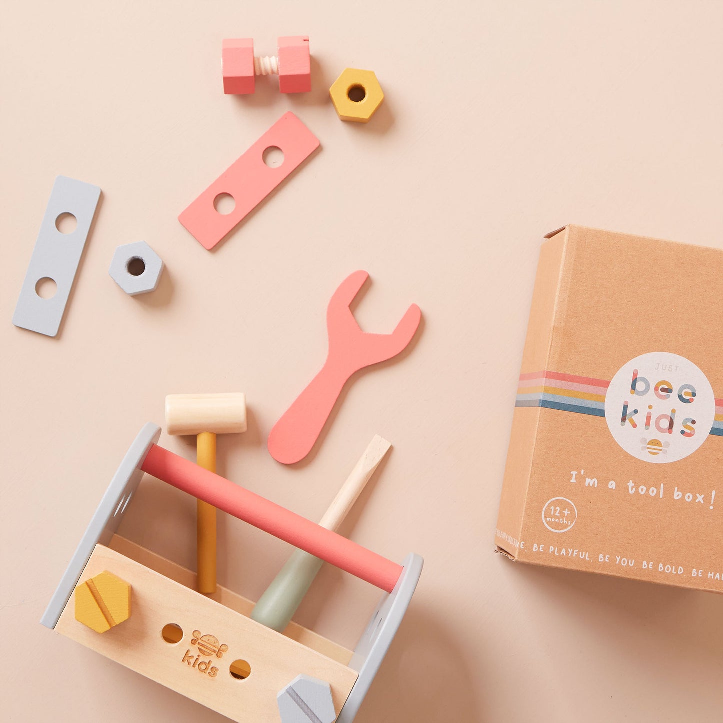 Colourful toy toolbox with tools and a box labelled 'just bee kids' on a beige background