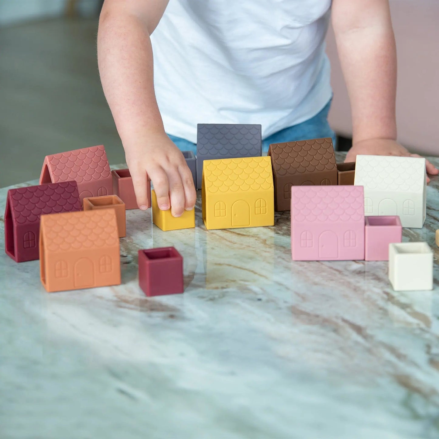 Child playing with colourful building blocks on a marble surface