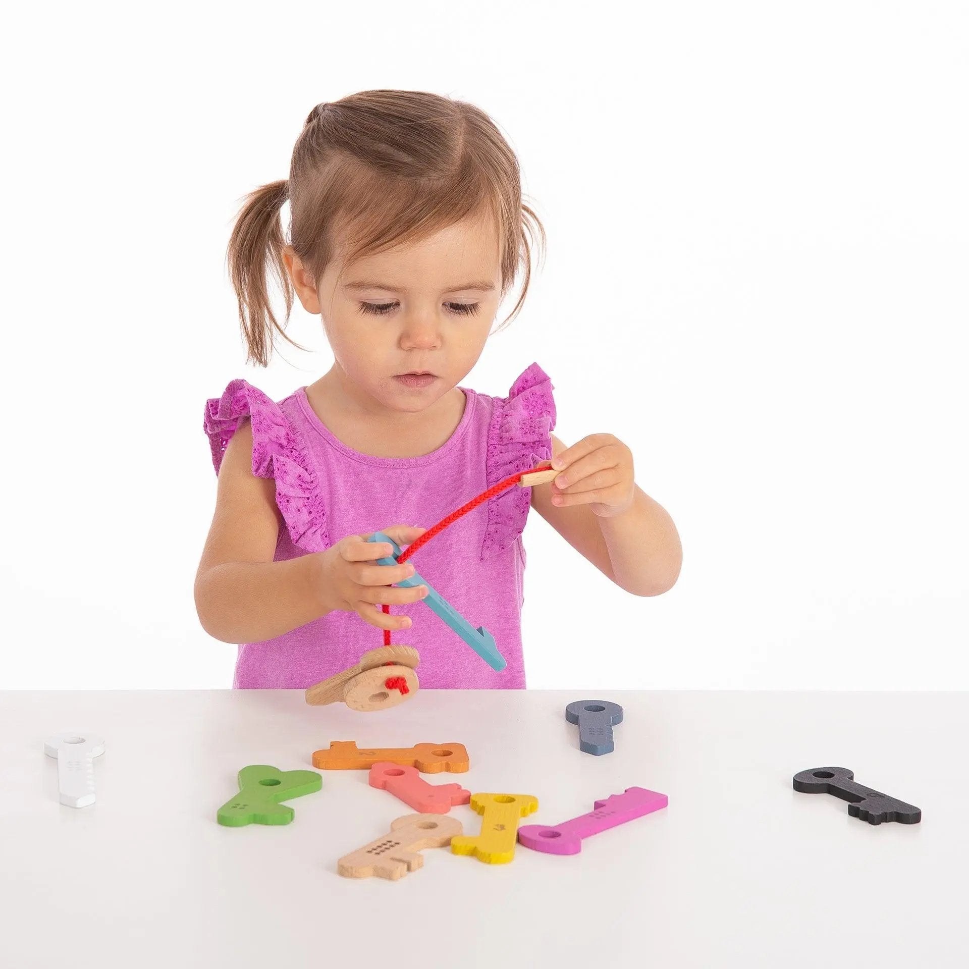 Child playing with colourful toy keys on a white surface