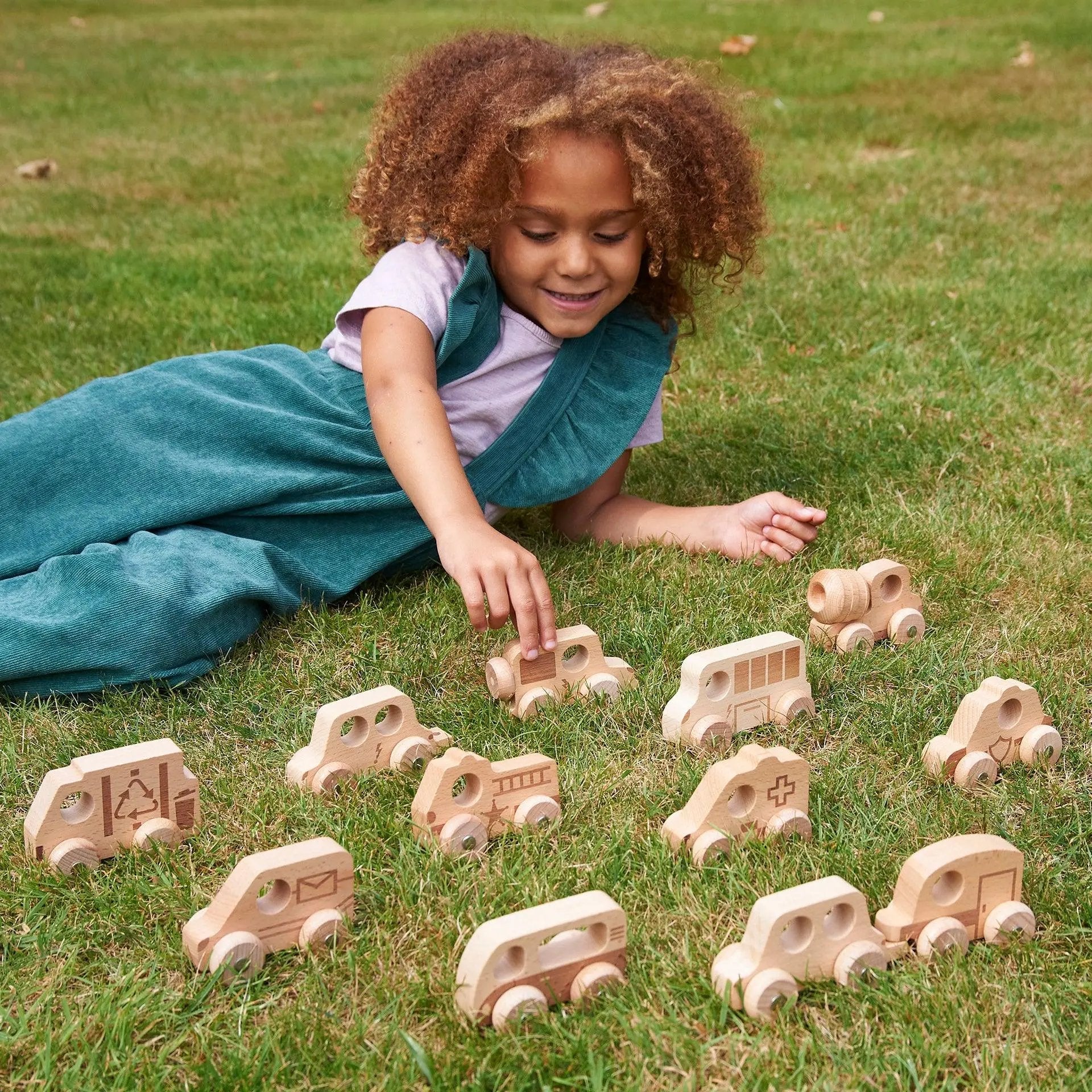 Child playing with wooden toy cars on grass