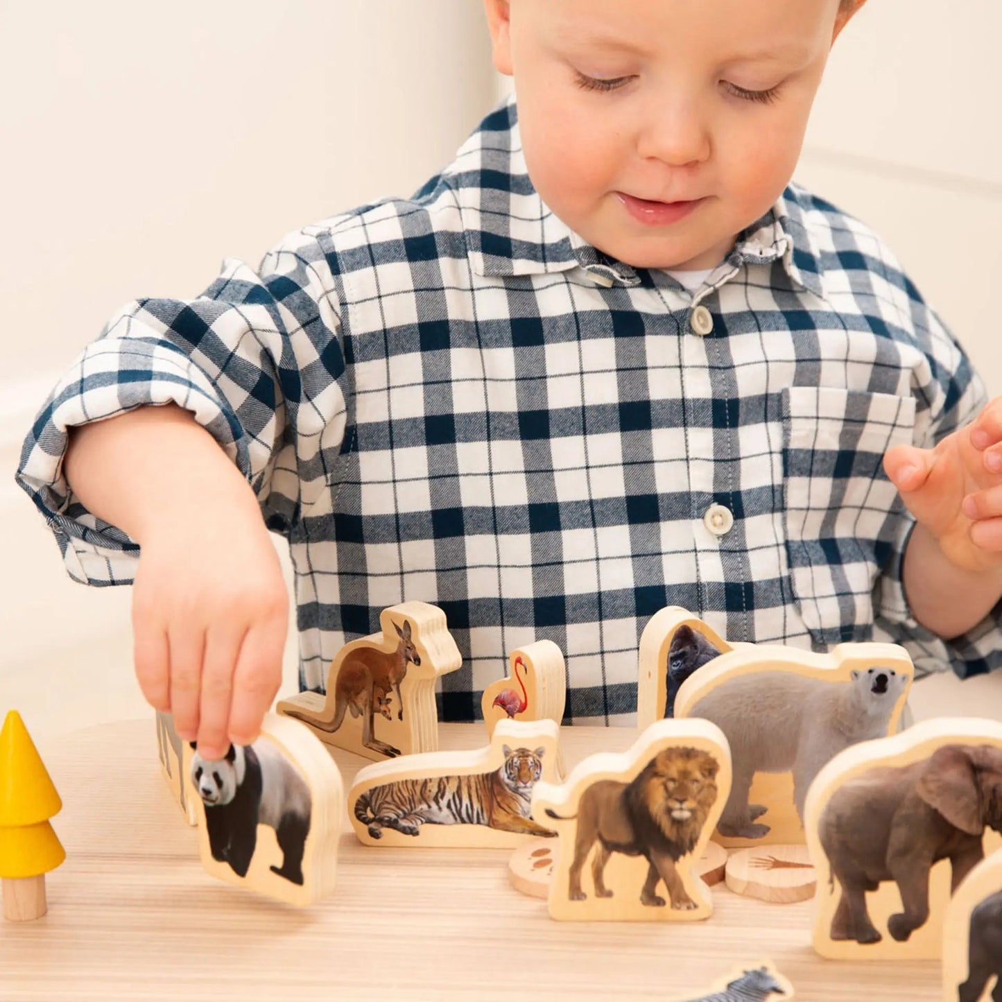 Child playing with wooden animal toys on a table