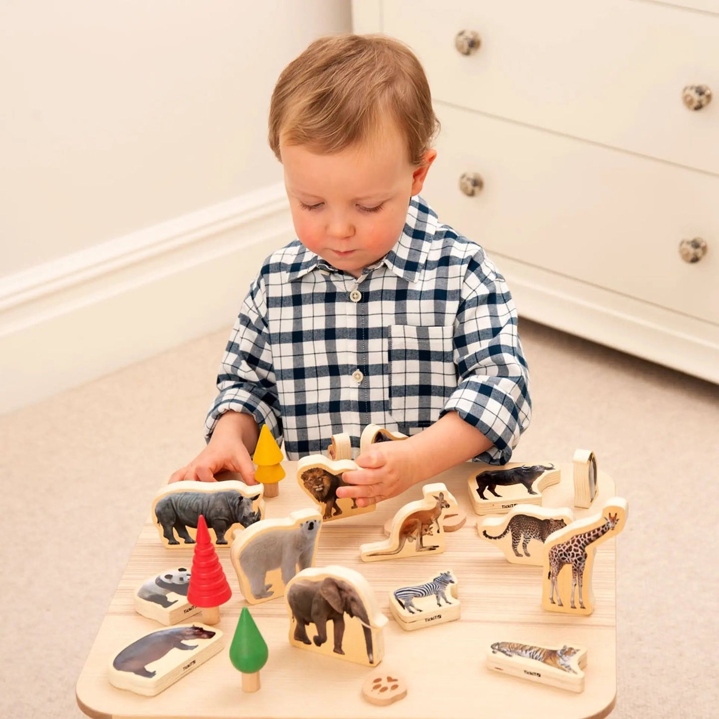Child playing with wooden animal blocks on a light-coloured floor.