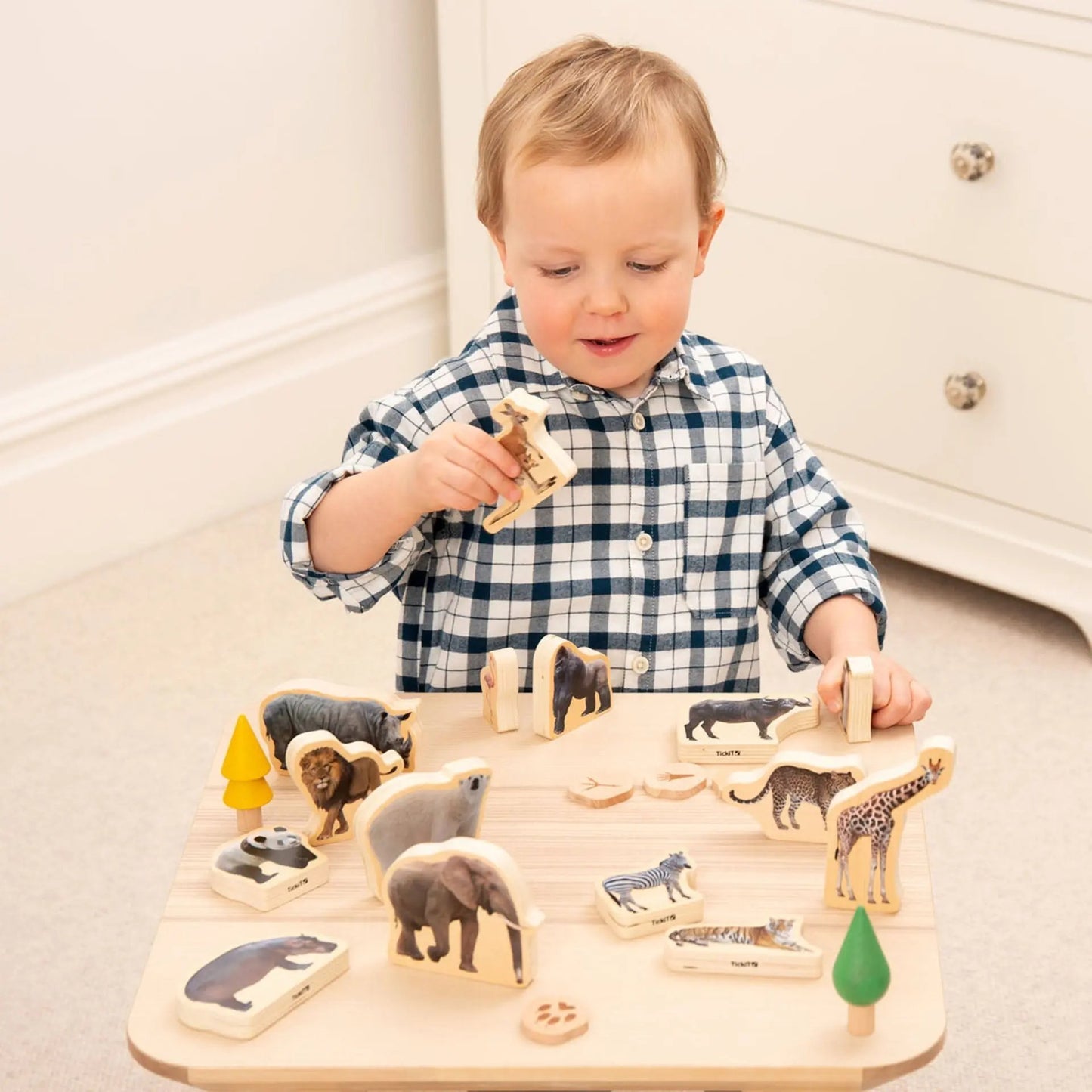 Child playing with a wooden animal puzzle on a table.