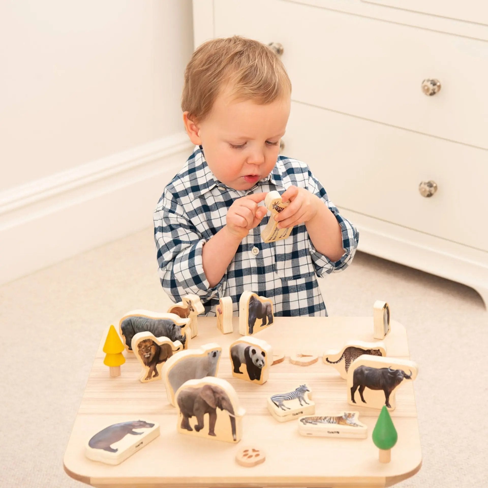Child playing with a wooden animal puzzle on a table.