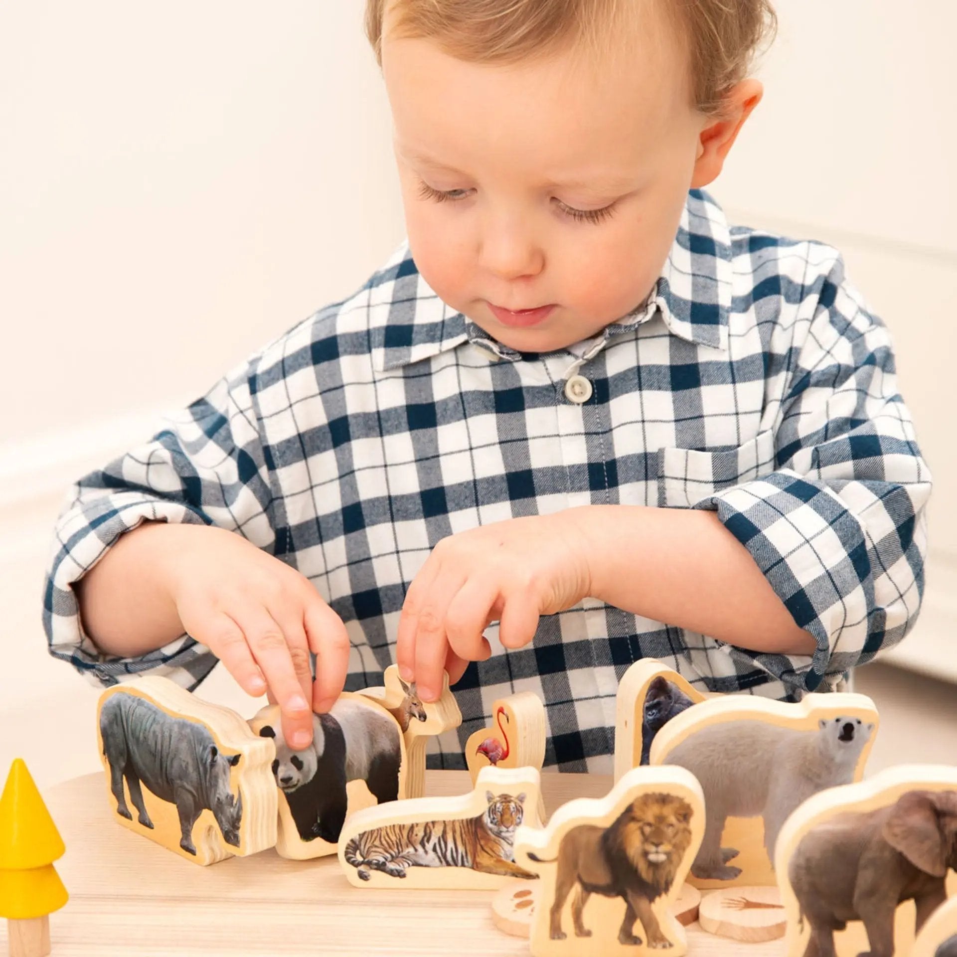 Child playing with wooden animal figurines on a light surface