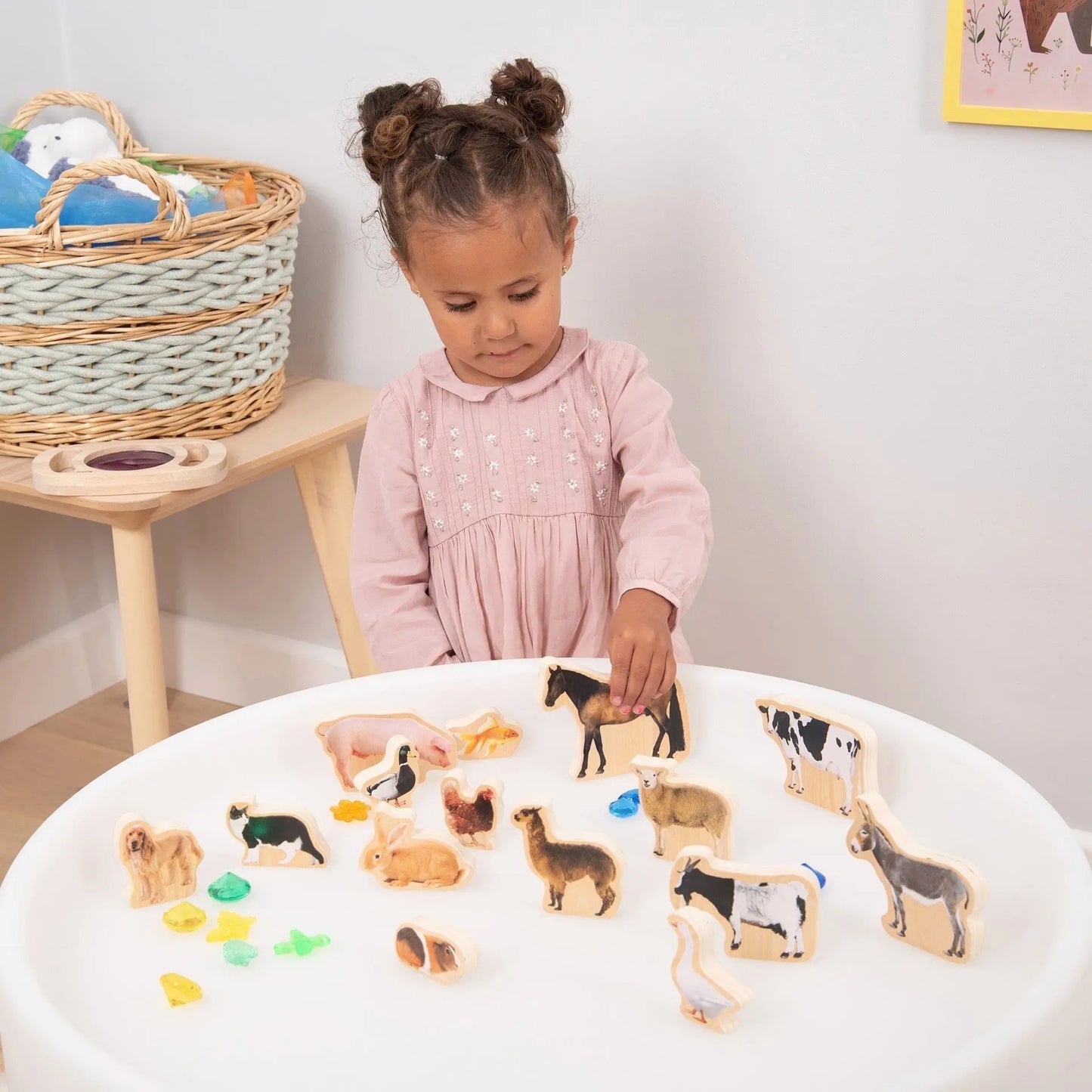 Child playing with animal figurines on a table in a room setting.