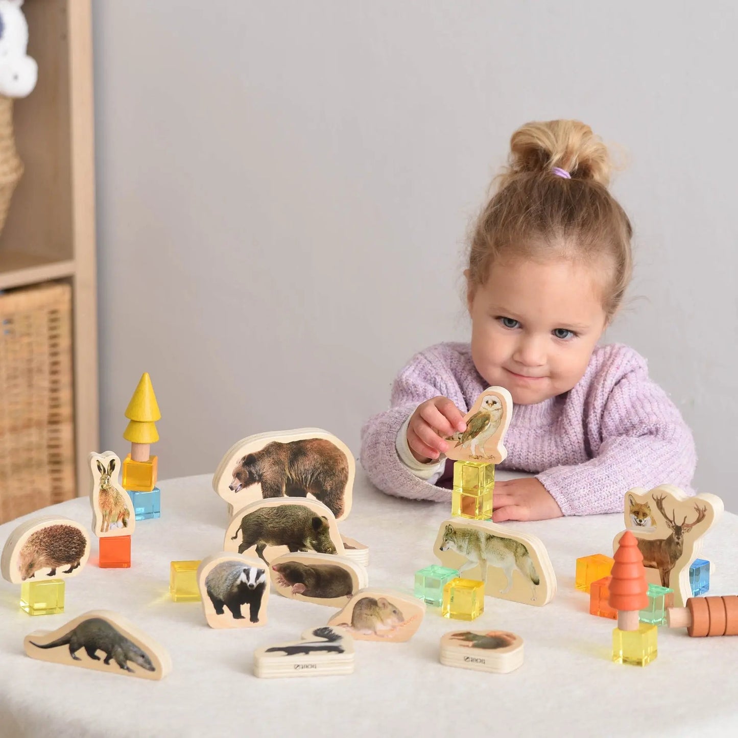 Child playing with animal-themed wooden toys on a light surface.