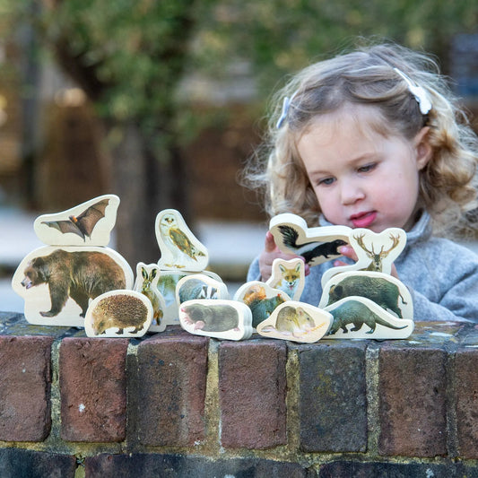 Child playing with animal figurines on a brick ledge outdoors