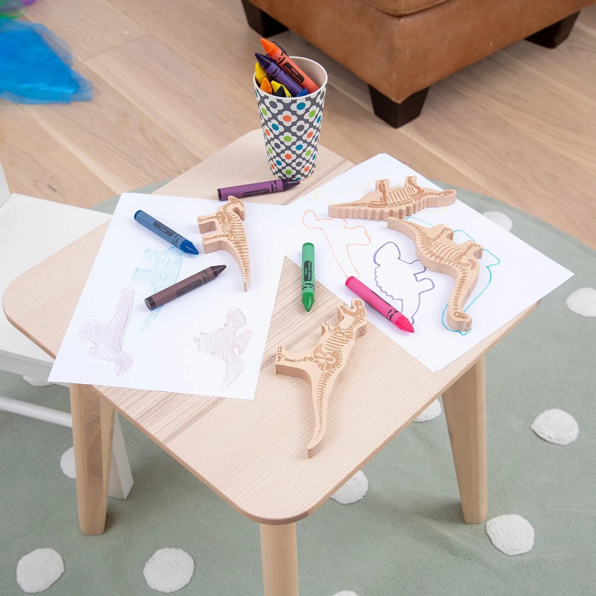 Children's table with wooden toys and colouring supplies on a carpeted floor.