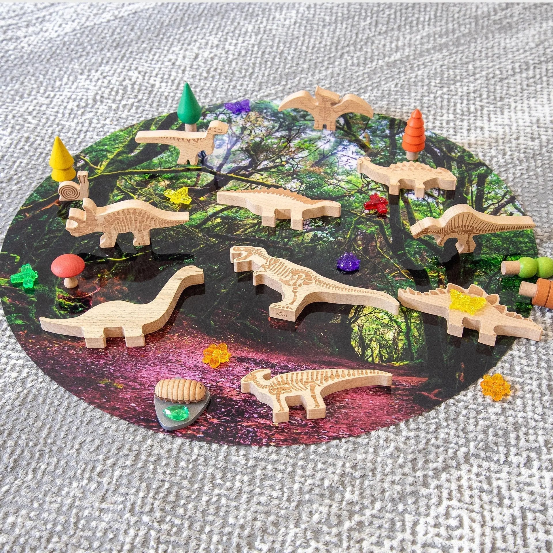 Wooden dinosaur toys on a round mat with a forest design