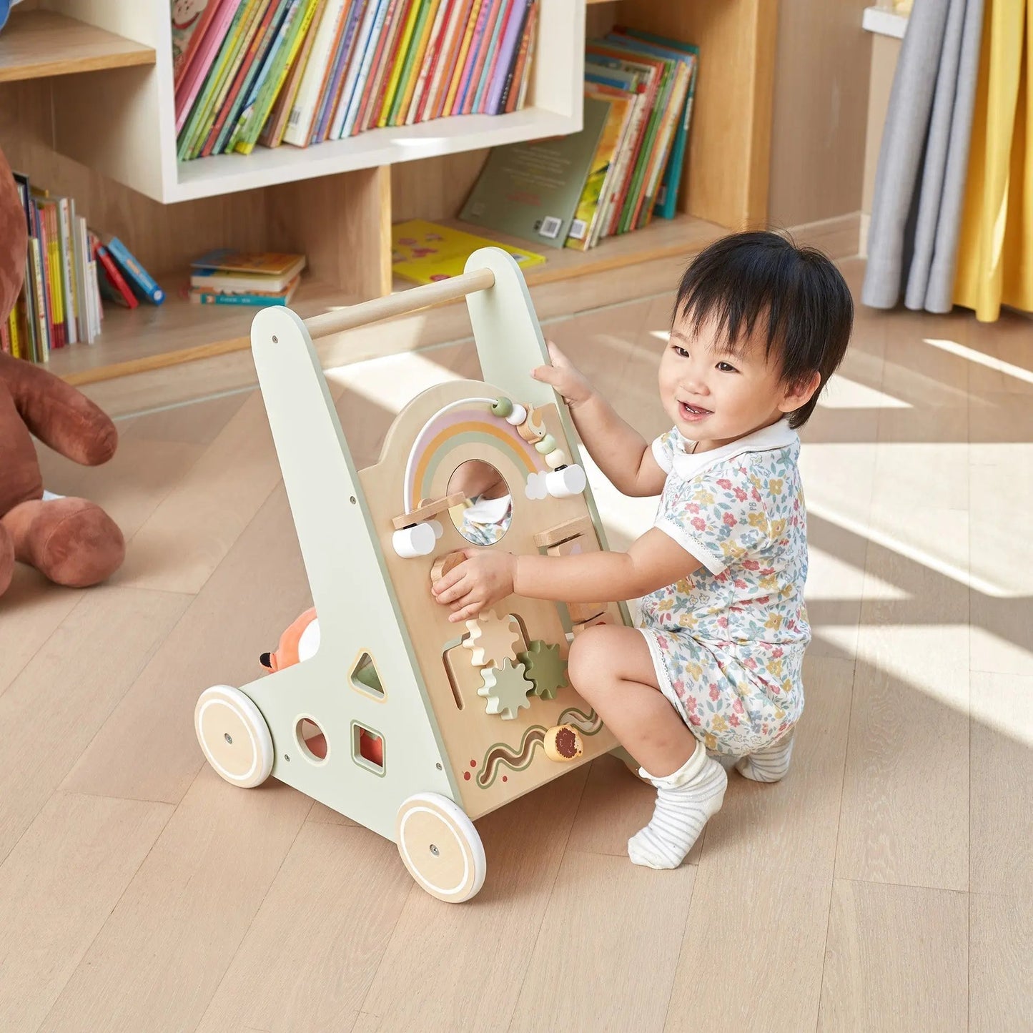 Child playing with a wooden toy in a room with books and toys.