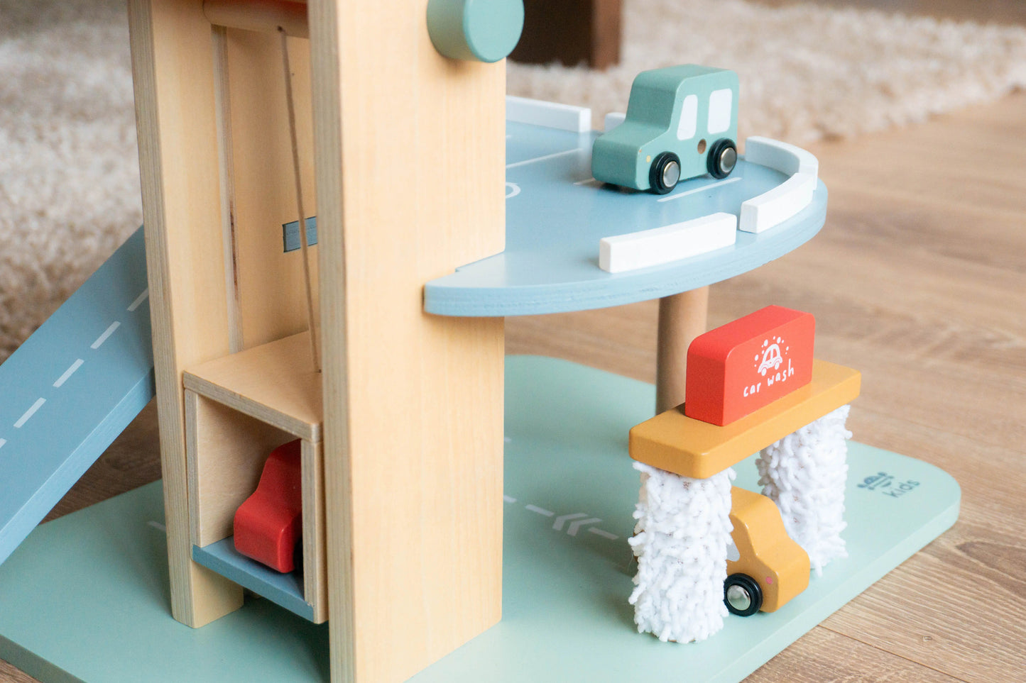 Wooden toy car ramp with cars on a wooden floor