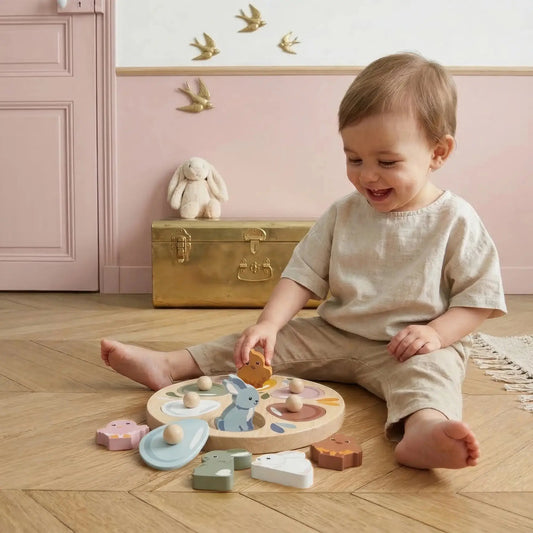 Child playing with wooden toys on a wooden floor in a room with pink walls and gold accents.