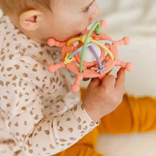 Close-up of a baby holding a silicone teething rattle, showing its easy-to-grasp design.
