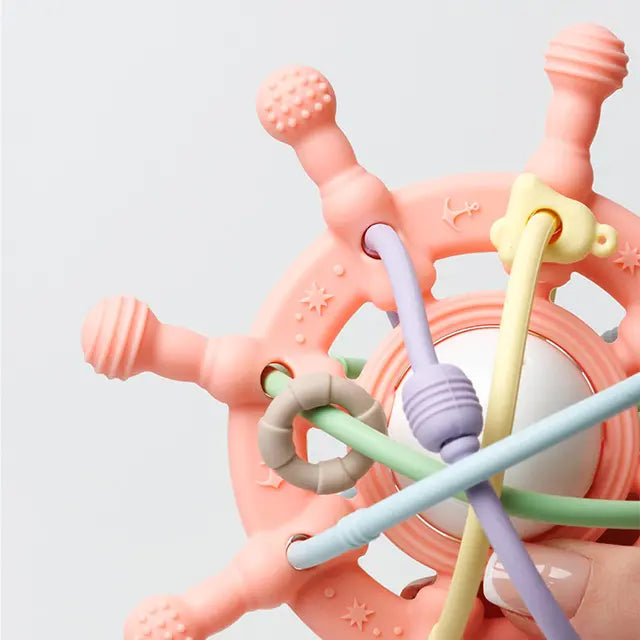 Close-up of a baby holding a silicone teething rattle, showing its easy-to-grasp design.