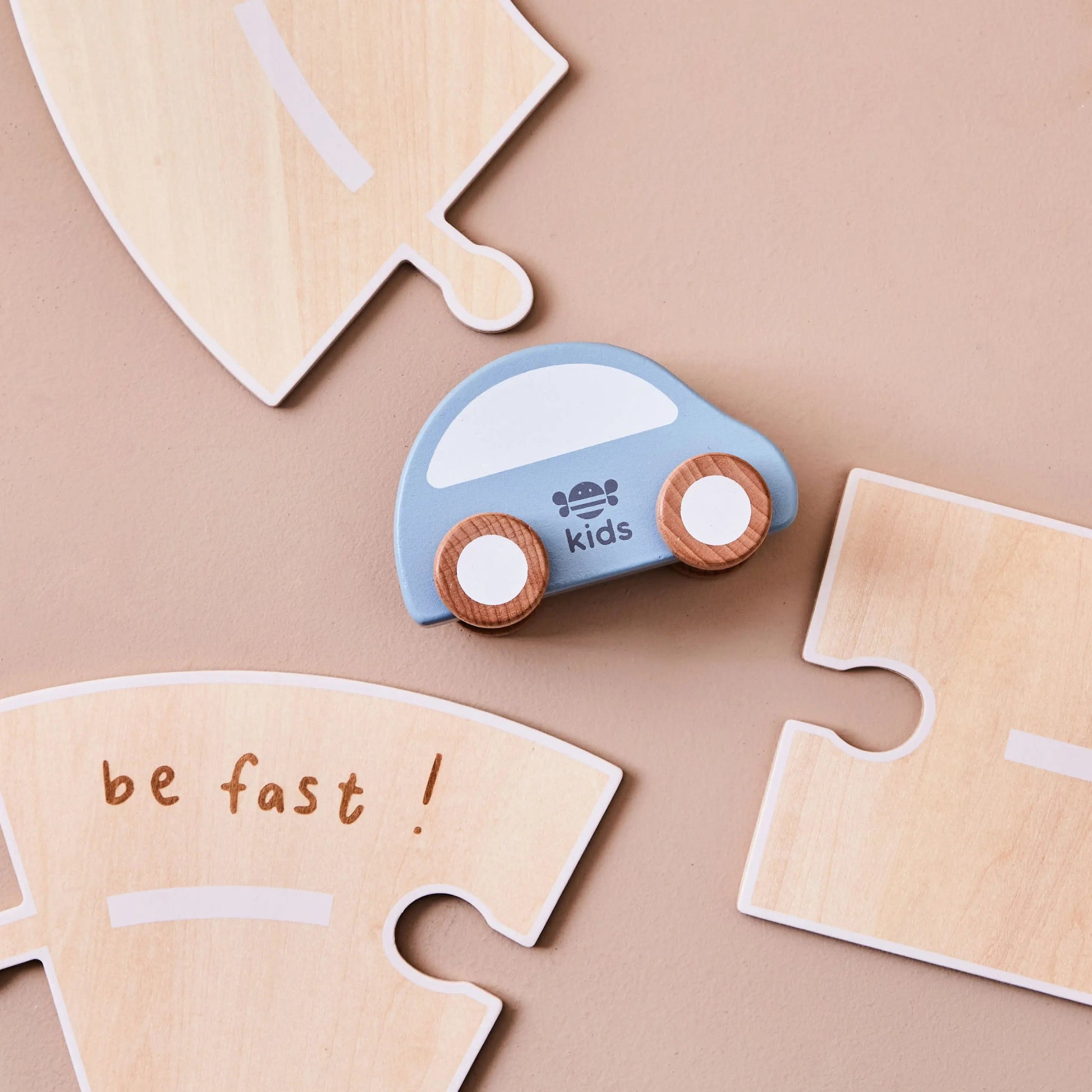 Wooden blue car toy with puzzle pieces on a beige background