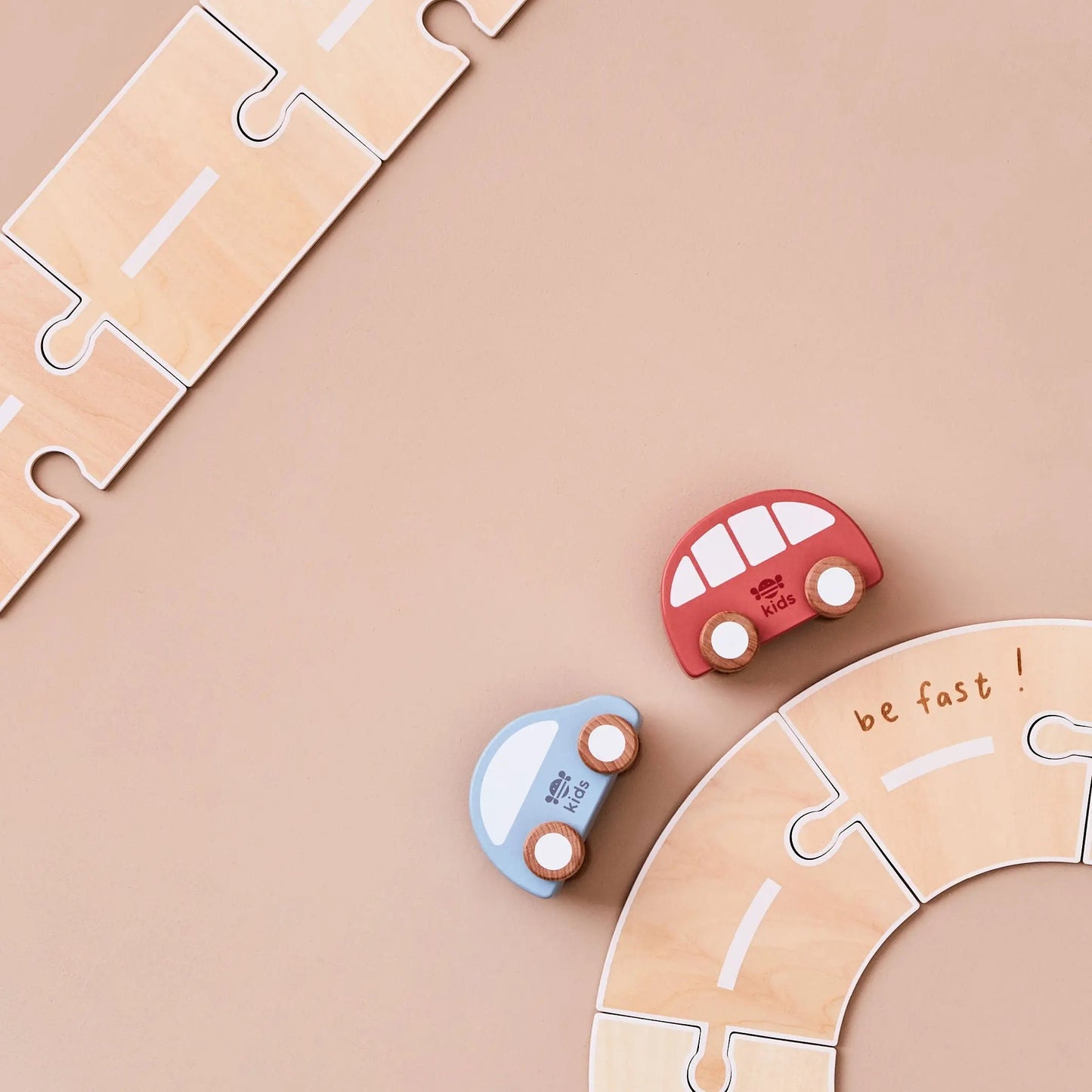 Wooden toy cars and puzzle pieces on a beige background