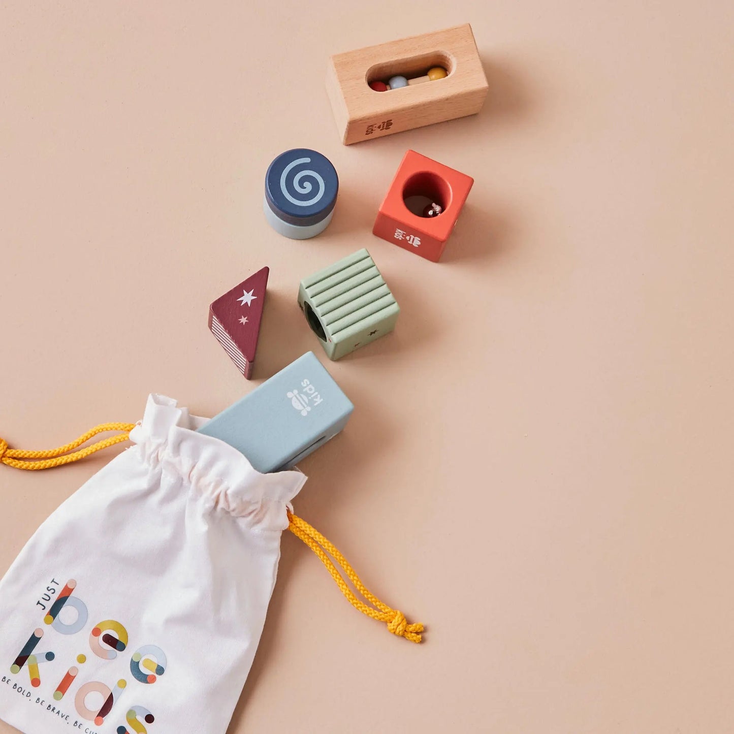 Colourful wooden shape blocks with a drawstring bag on a beige background