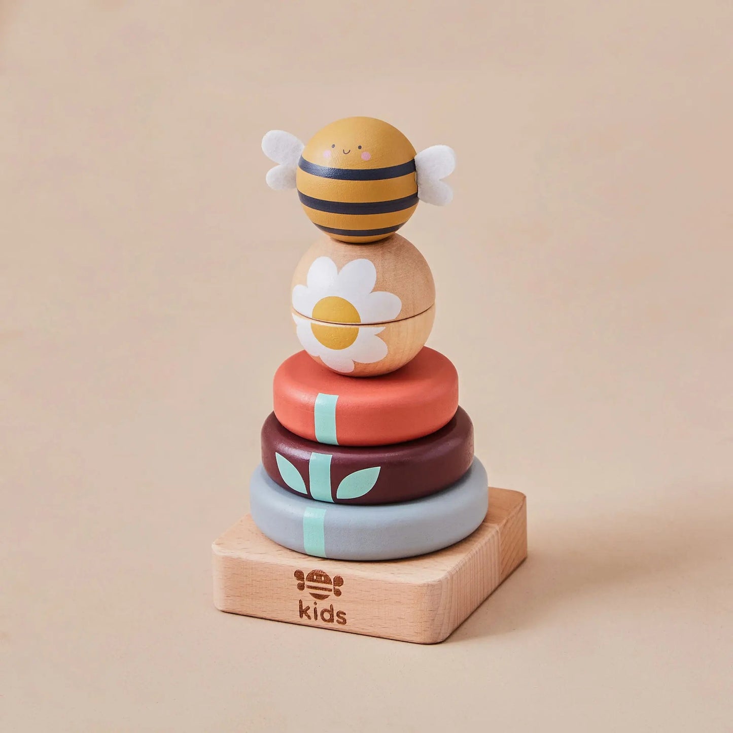 Stack of colourful wooden toys with bee and flower design on a beige background