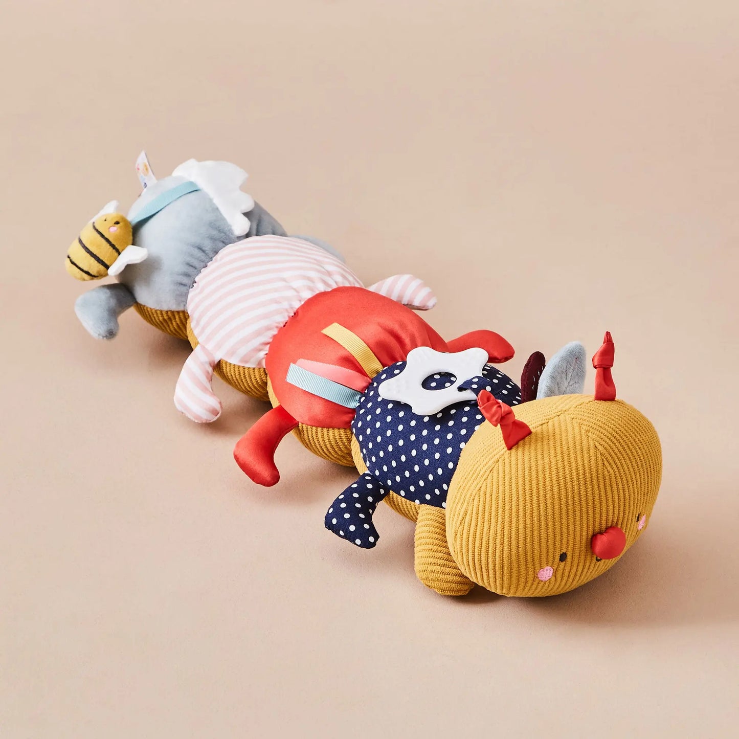 Colourful plush caterpillar toy arranged in a row on a beige background