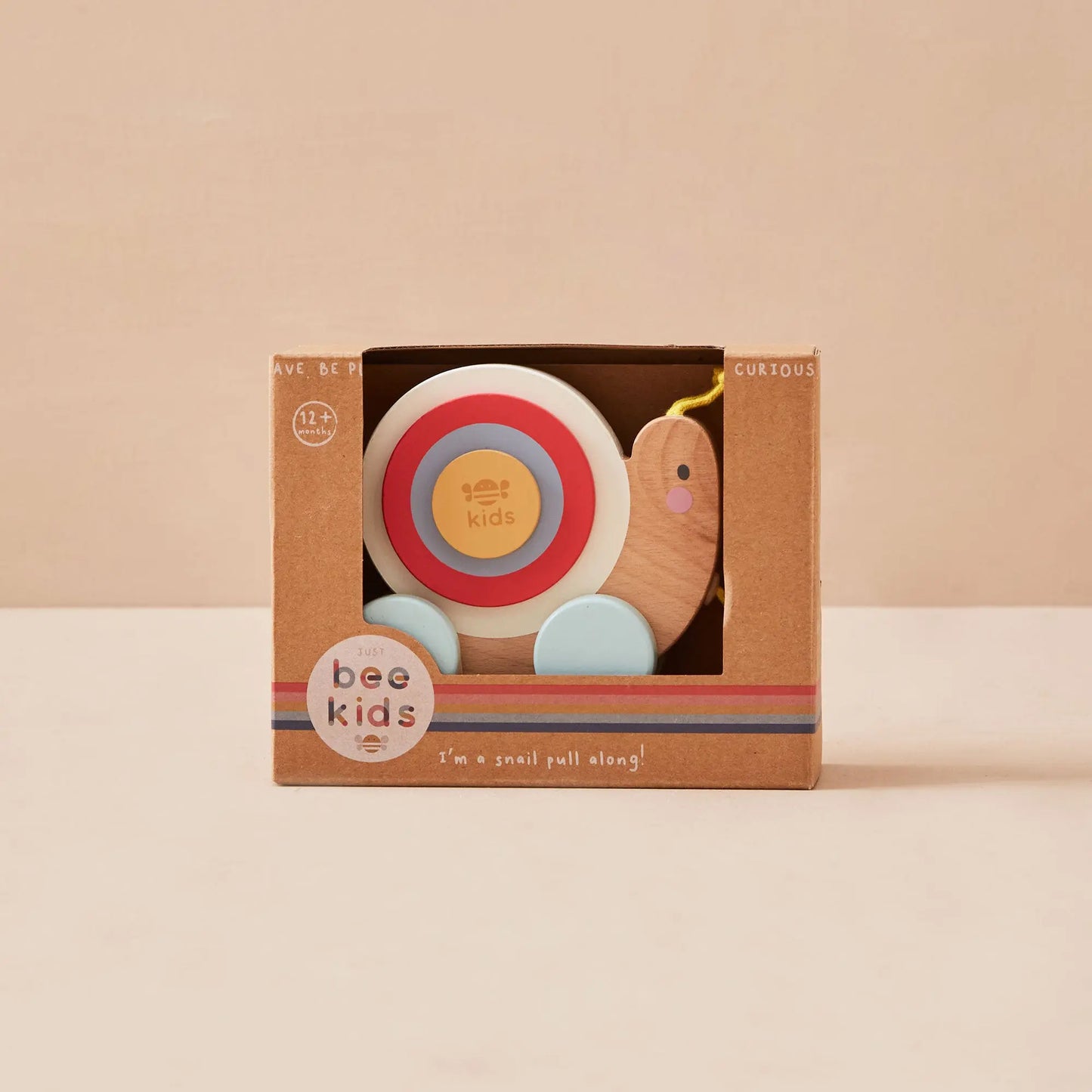 Children's snail toy in a brown box with 'just bee kids' branding on a beige background