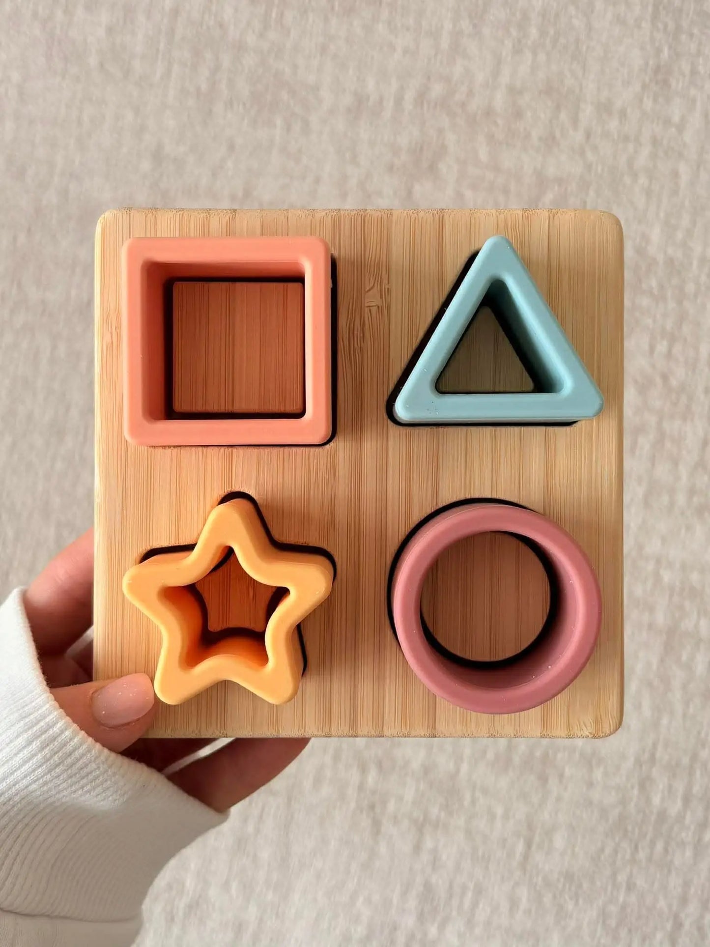 Wooden shape sorting toy with colorful shapes on a beige background