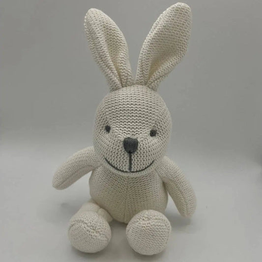 A cream-coloured knitted bunny plush toy with a black embroidered nose and eyes, sitting against a neutral grey background.