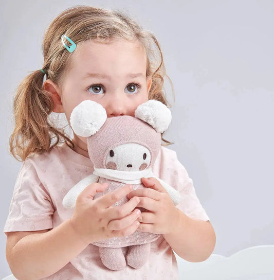 Child holding a plush toy with a neutral background
