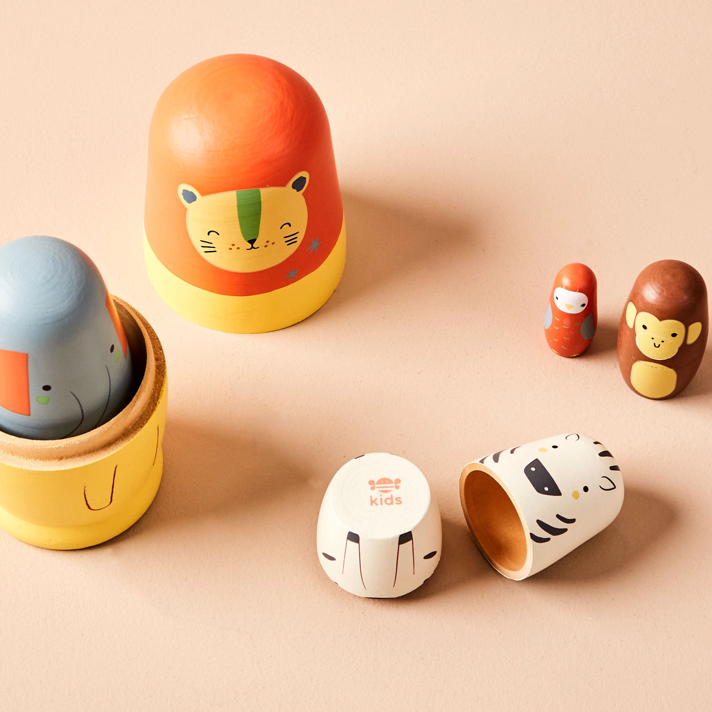 Set of colourful wooden nesting dolls with safari designs on a beige background