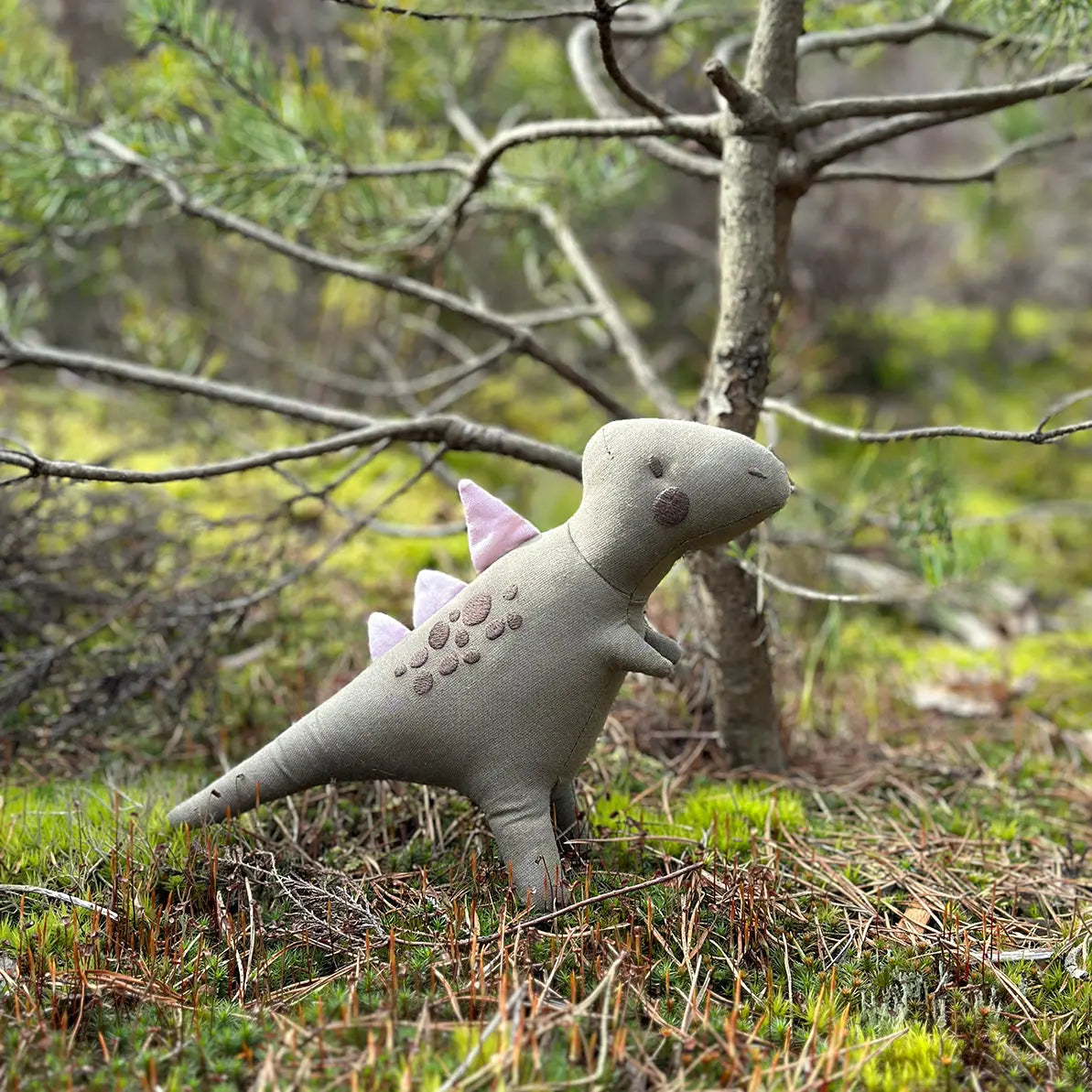 Plush dinosaur toy in a forest setting