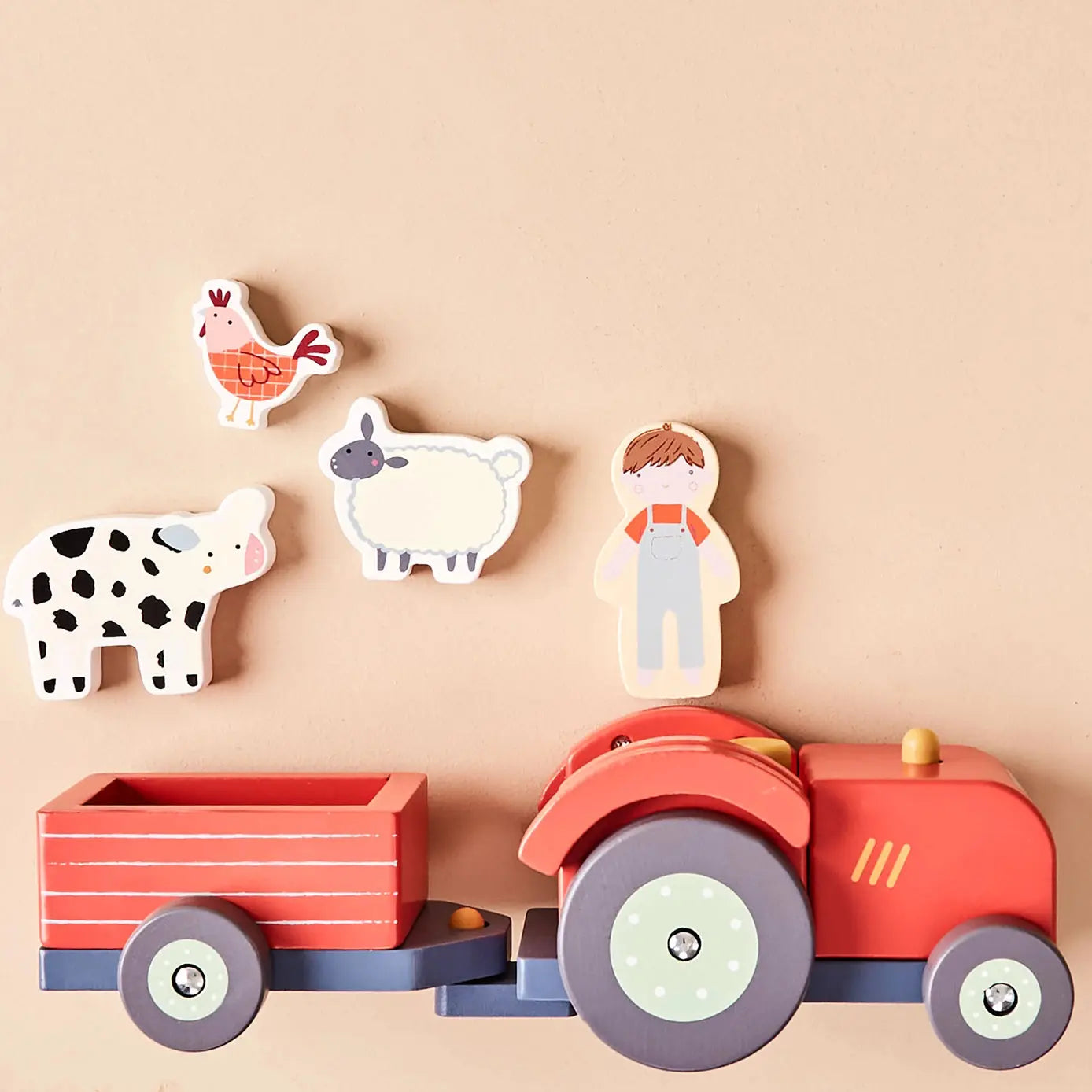 Wooden toy set with a red tractor, trailer, and farm animals on a beige background