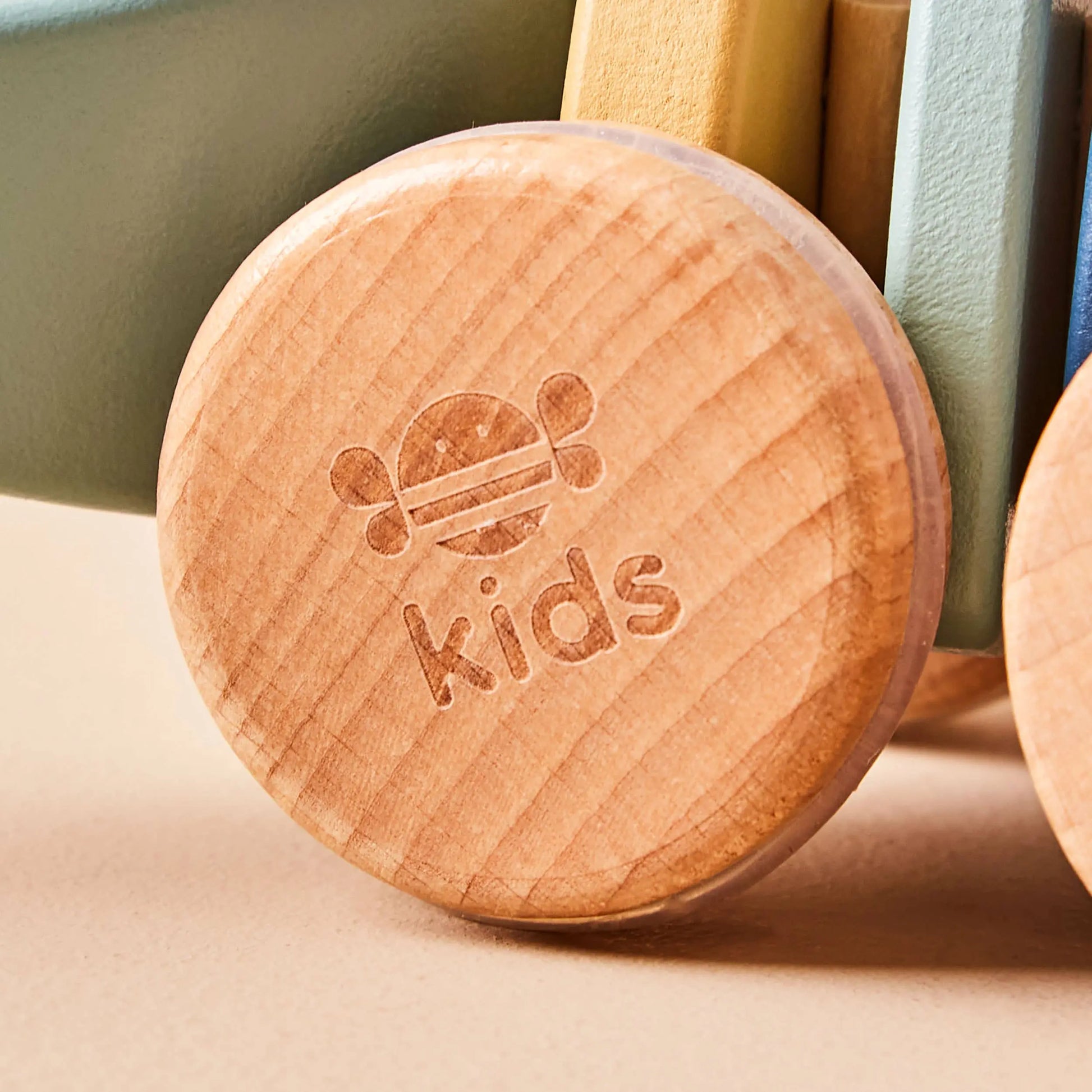 Wooden wheel with 'kids' engraving on a neutral background