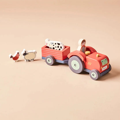 Wooden toy tractor with trailer and farm animals on a beige background