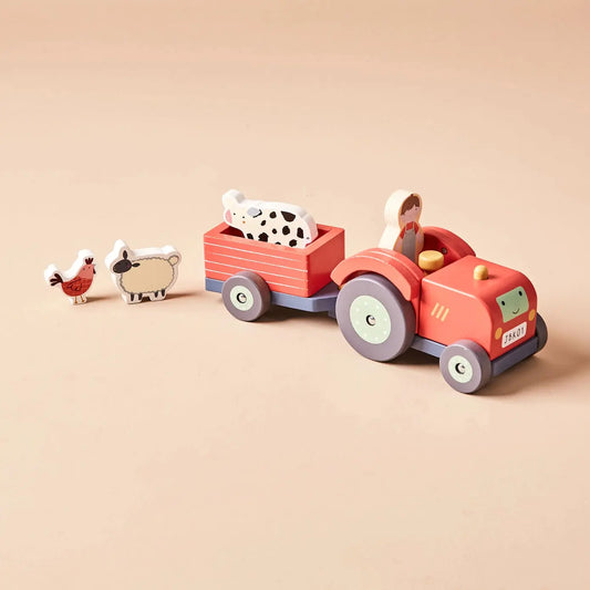 Wooden toy tractor with trailer and farm animals on a beige background