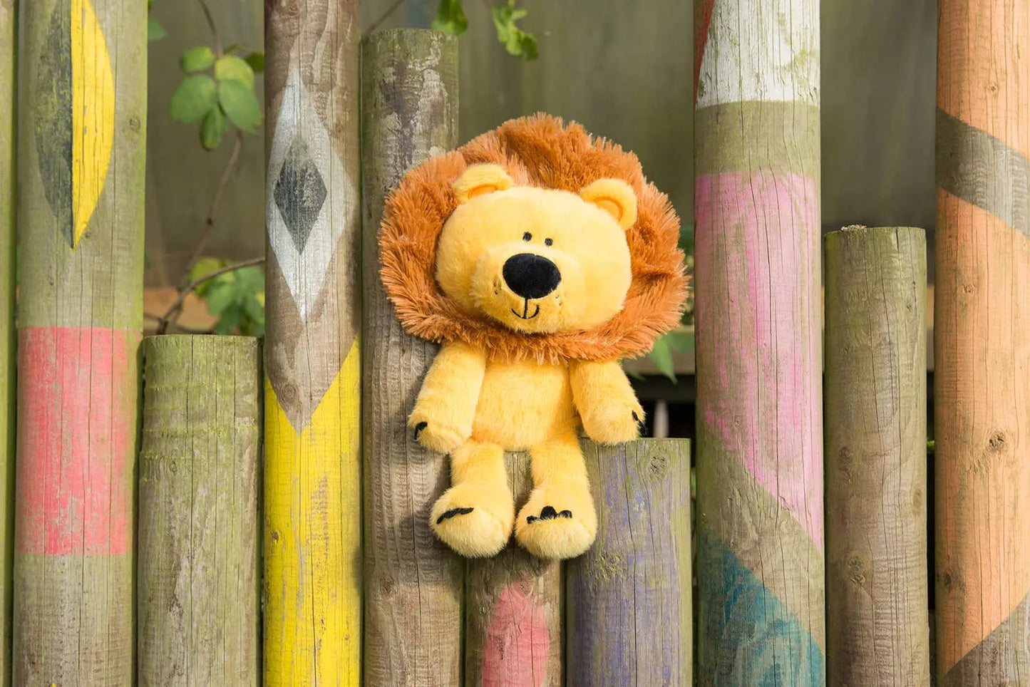 Plush lion toy on a wooden fence with colourful paint designs