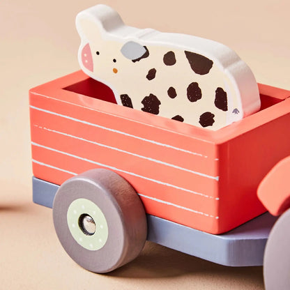 Wooden toy cow in a red wagon with a beige background