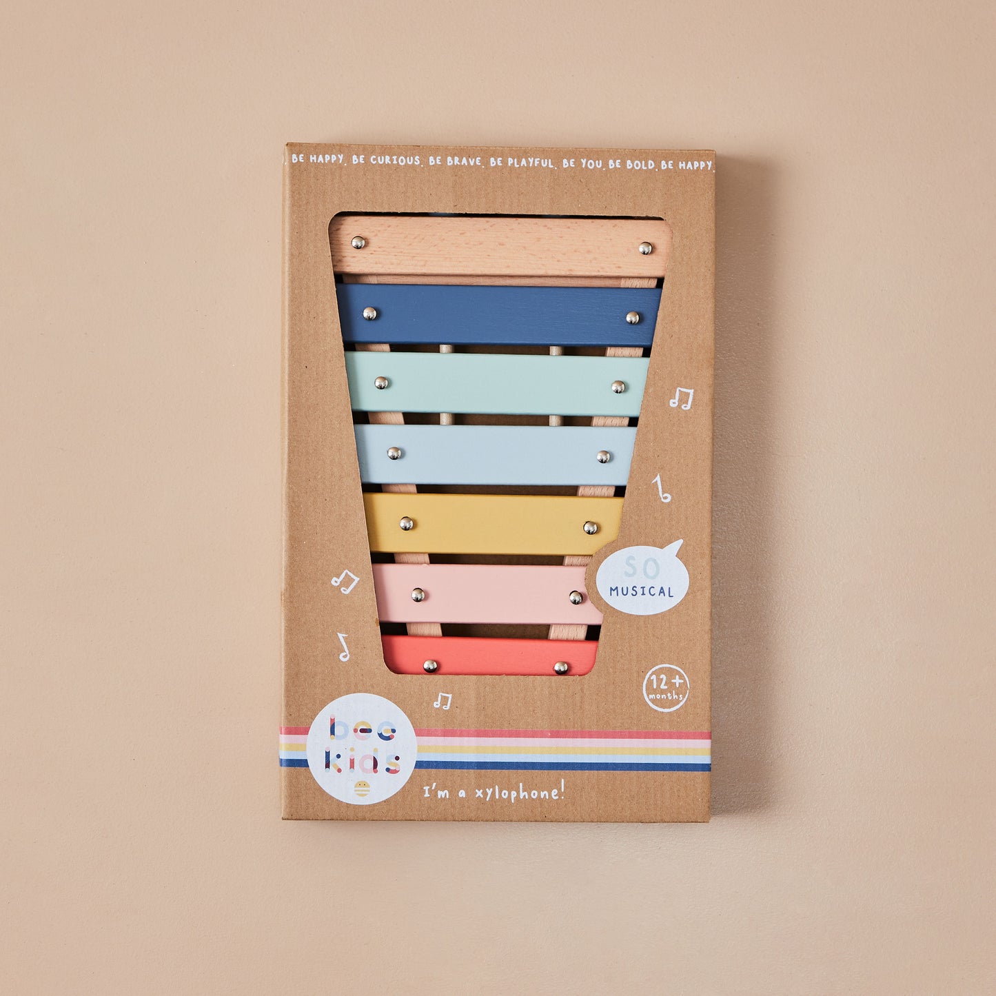 Colourful xylophone toy in a cardboard box on a beige background