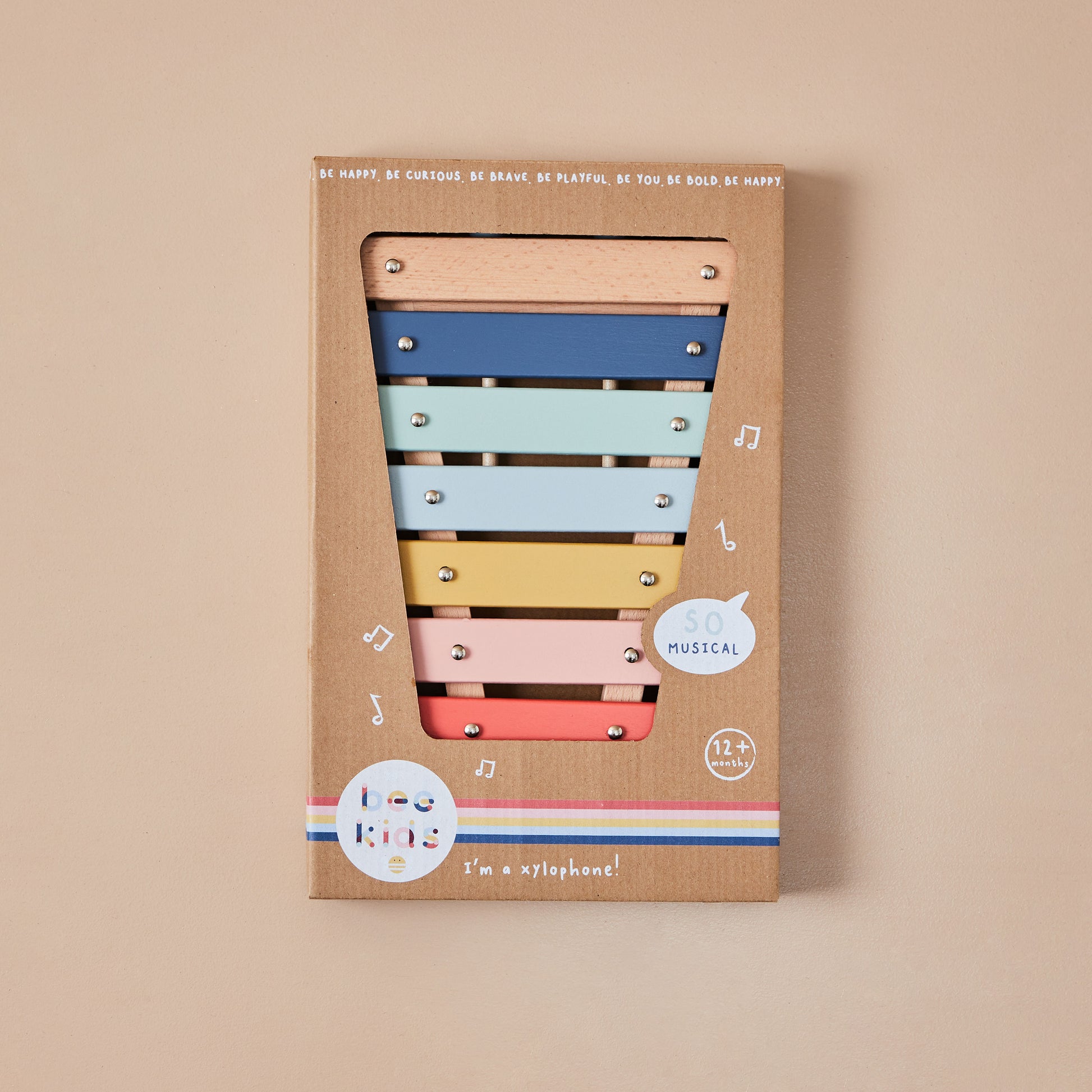 Colourful xylophone toy in a cardboard box on a beige background