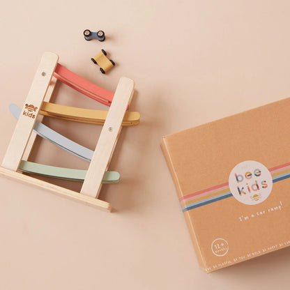 Colourful wooden toy car ramp with 'just bee kids' branding on a beige background