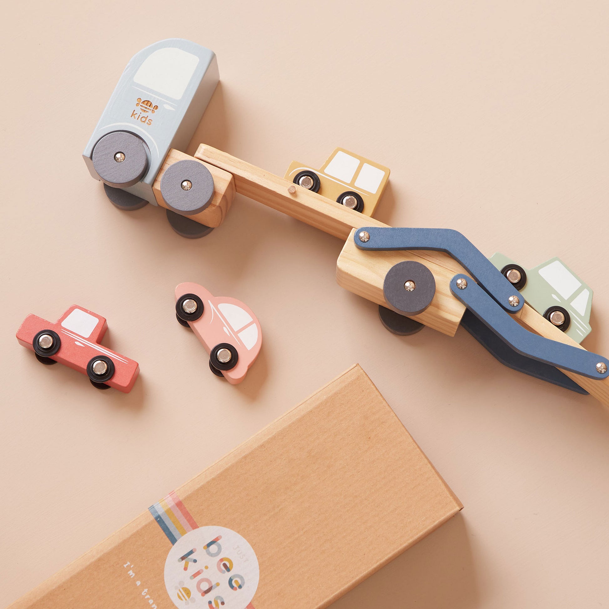 Wooden toy set with cars and a transporter on a beige background