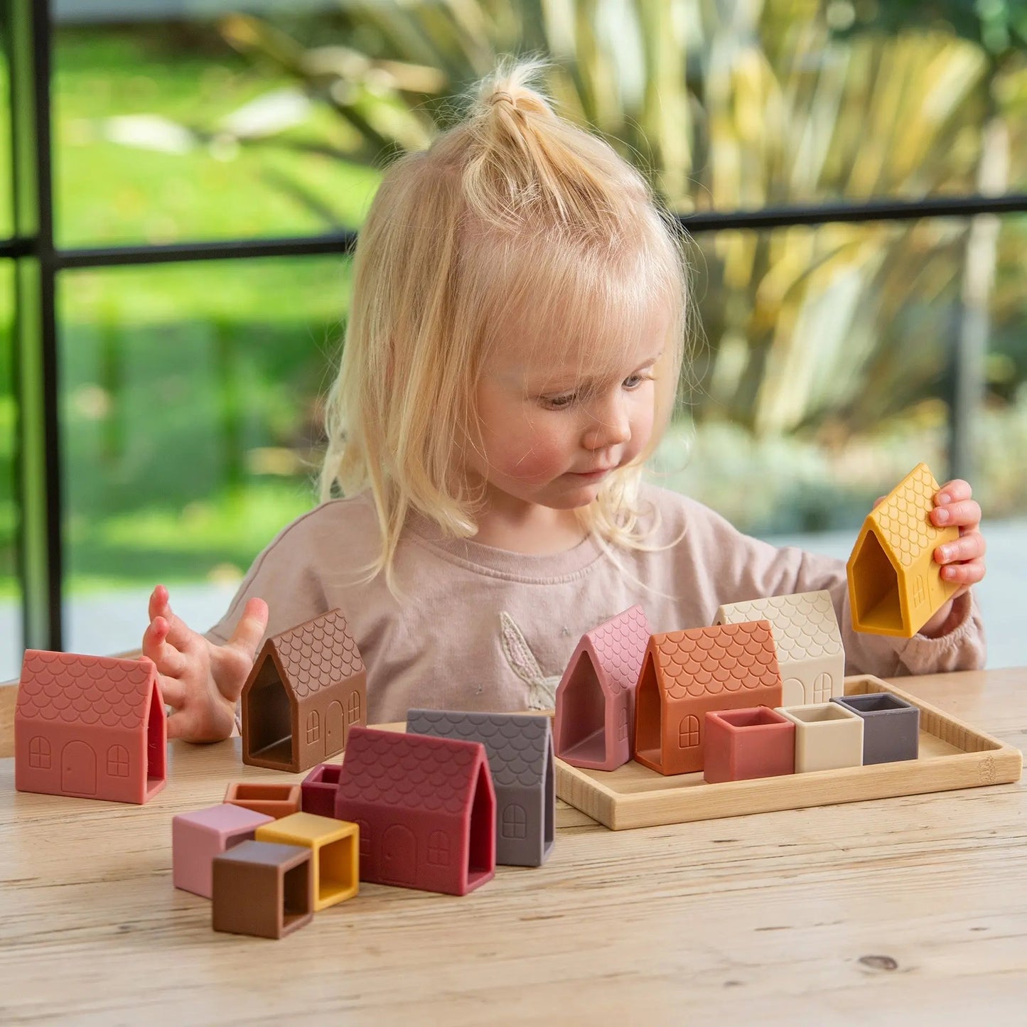 Child playing with colourful wooden blocks on a table outdoors