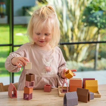 Child playing with colourful building blocks on a table outdoors.
