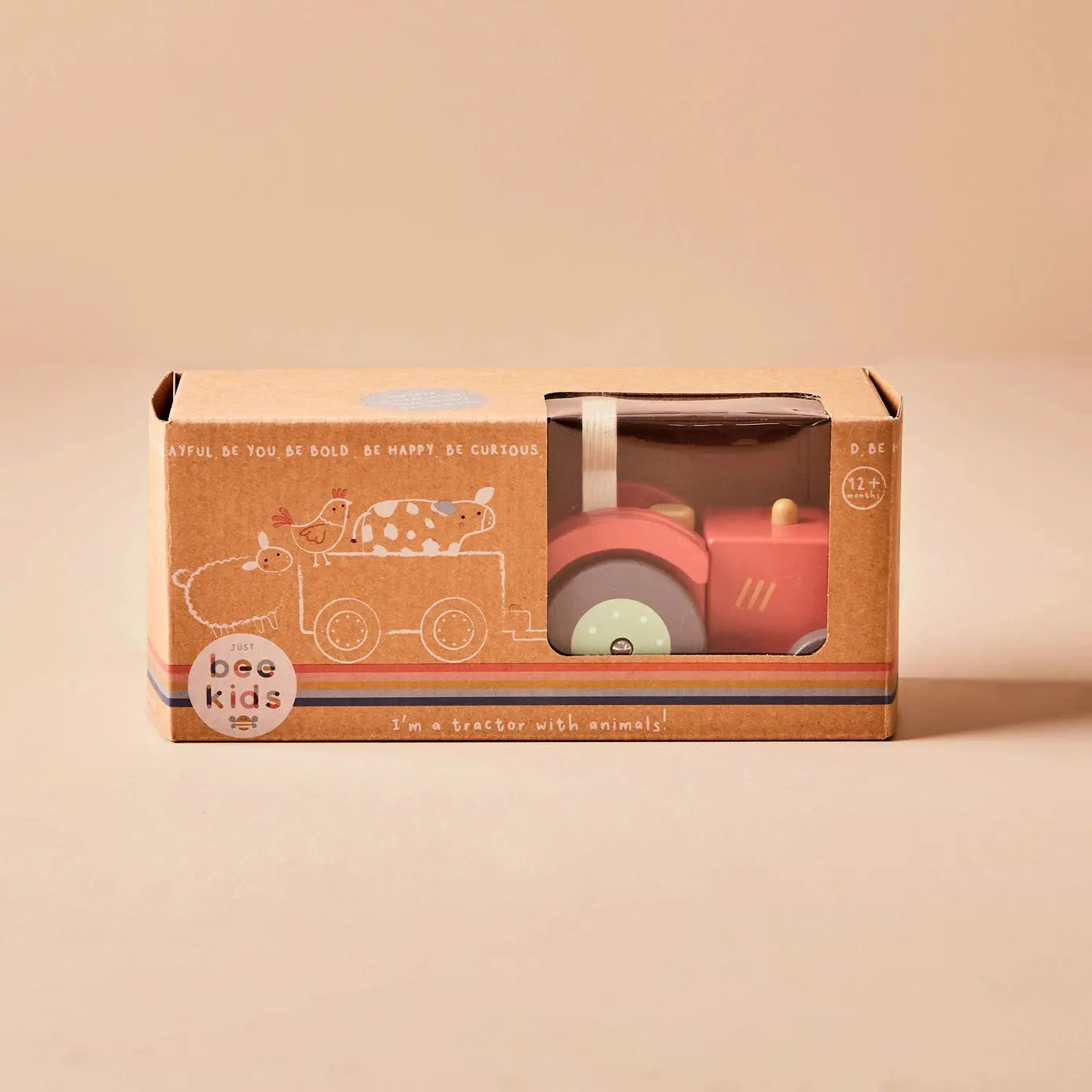 Toy tractor in a 'just bee kids' box on a beige background