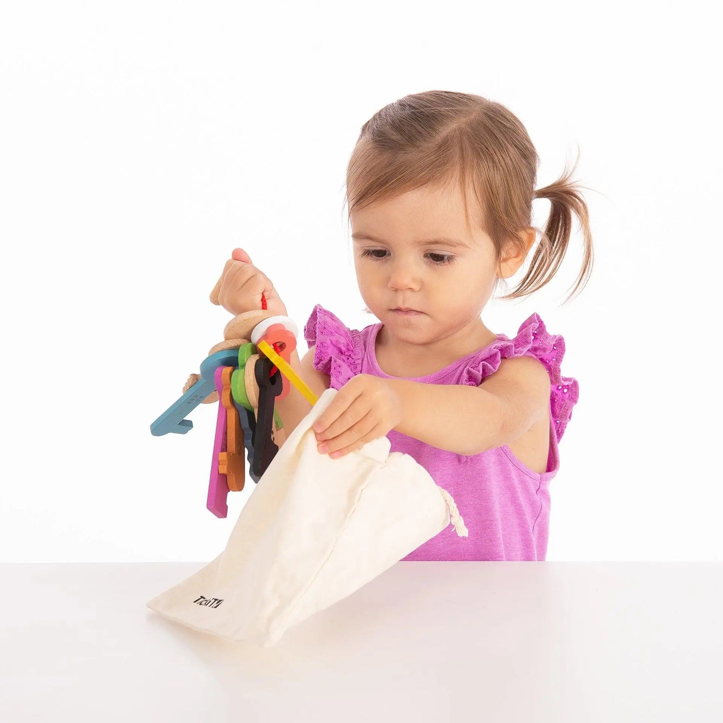 Child playing with colourful keys and bag on a white background