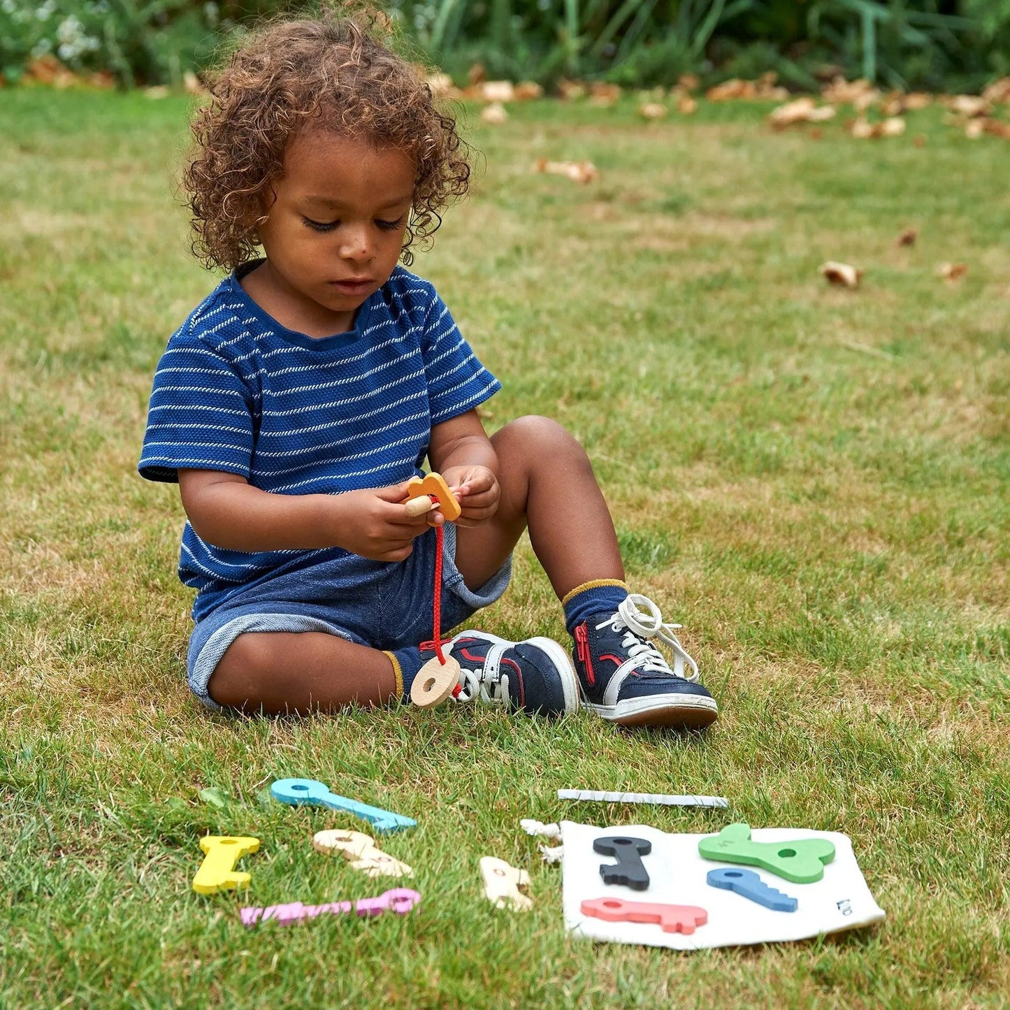 Child playing with colourful keys on grass