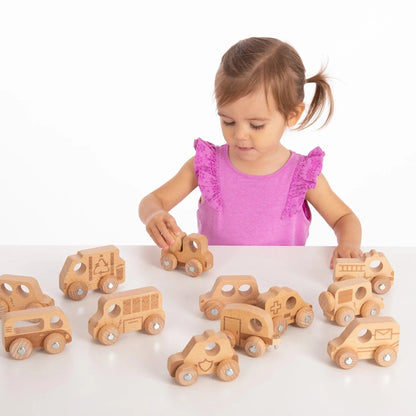 Child playing with wooden toy cars on a white surface